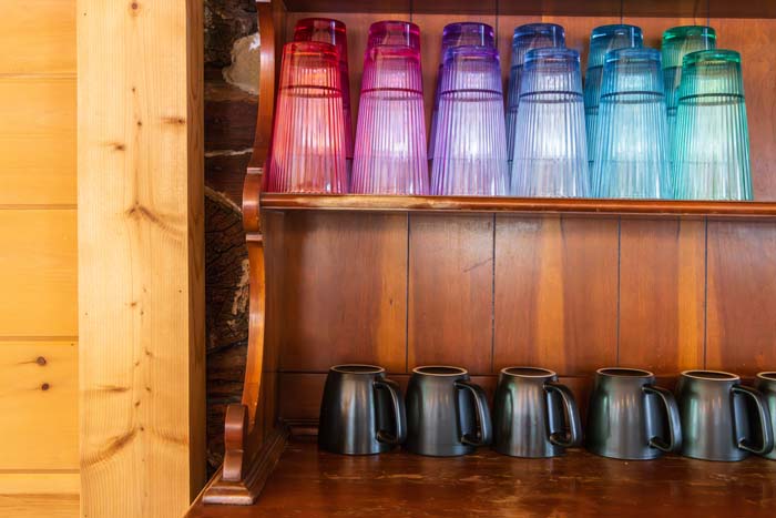 Colorful drinking glasses and coffee mugs on wood shelves at High Point Lodge