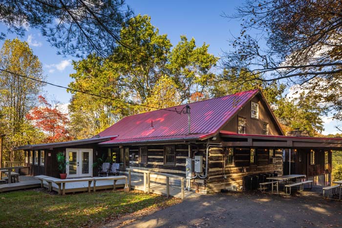 Log cabin with red roof and picnic tables in fall at High Point Lodge