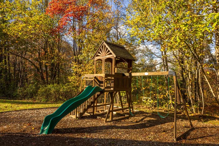 Wooden playset with slide and swings in the fall woods at High Point Lodge