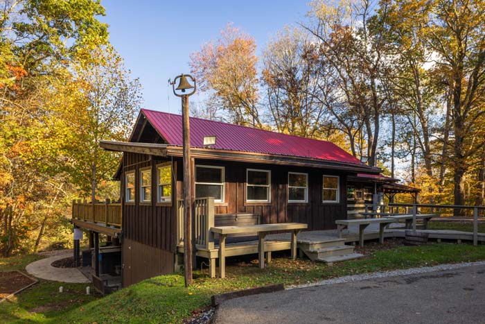 Log cabin with red roof, deck and picnic tables at High Point Lodge