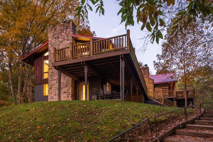 Lodge wing with stone chimney and deck at dusk at High Point Lodge