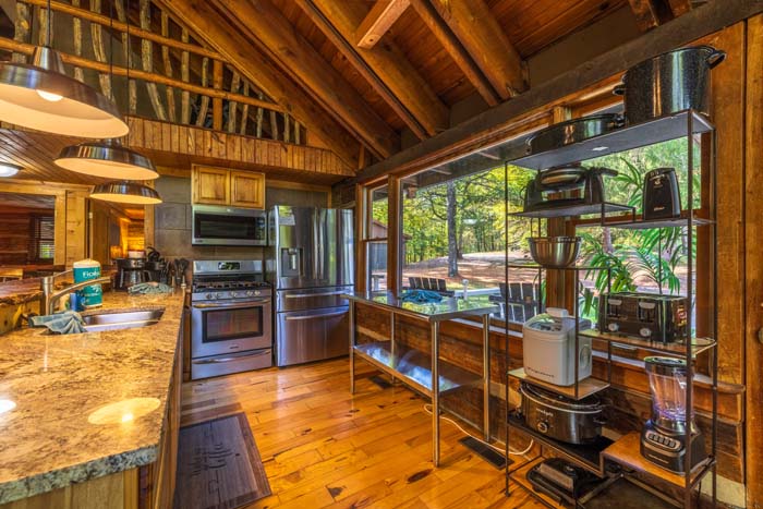 Kitchen with granite island and open shelving under wood beams at High Point Lodge