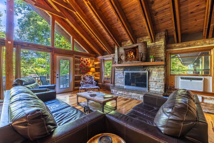 Great room with leather sofas and stone fireplace under a vaulted ceiling at High Point Lodge