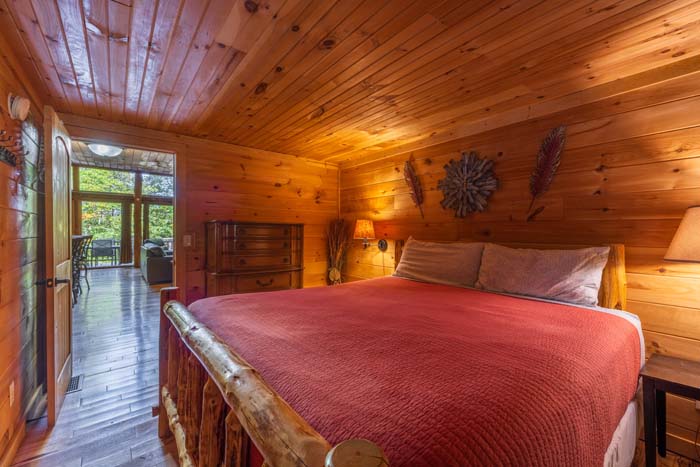 Bedroom with log bed and red quilt by the hallway door at High Point Lodge
