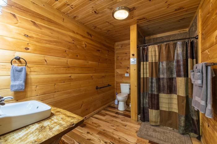 Bathroom with vessel sink, shower and wood walls at High Point Lodge