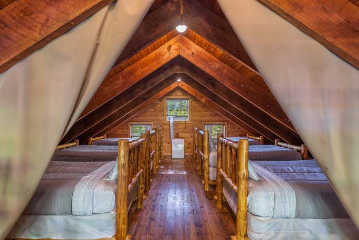 Loft with rows of log beds under the A frame ceiling at High Point Lodge