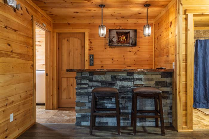 Stone bar with two bar stools and fireplace TV at High Point Lodge