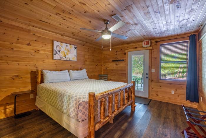 Bedroom with log bed, ceiling fan and outside door at High Point Lodge