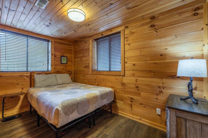 Bedroom with queen bed, lamp and two windows at High Point Lodge